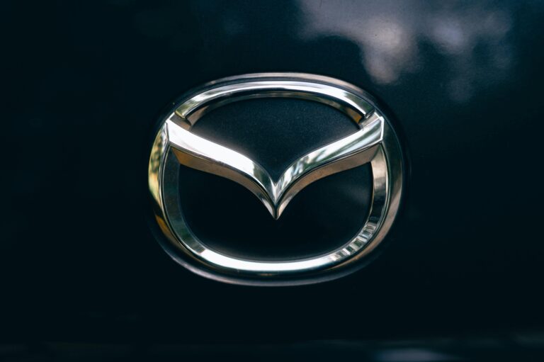 Close-up of a shiny metallic car logo on a dark surface.